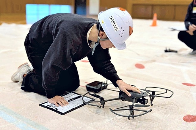 ドローンの飛行前点検を行う学生
