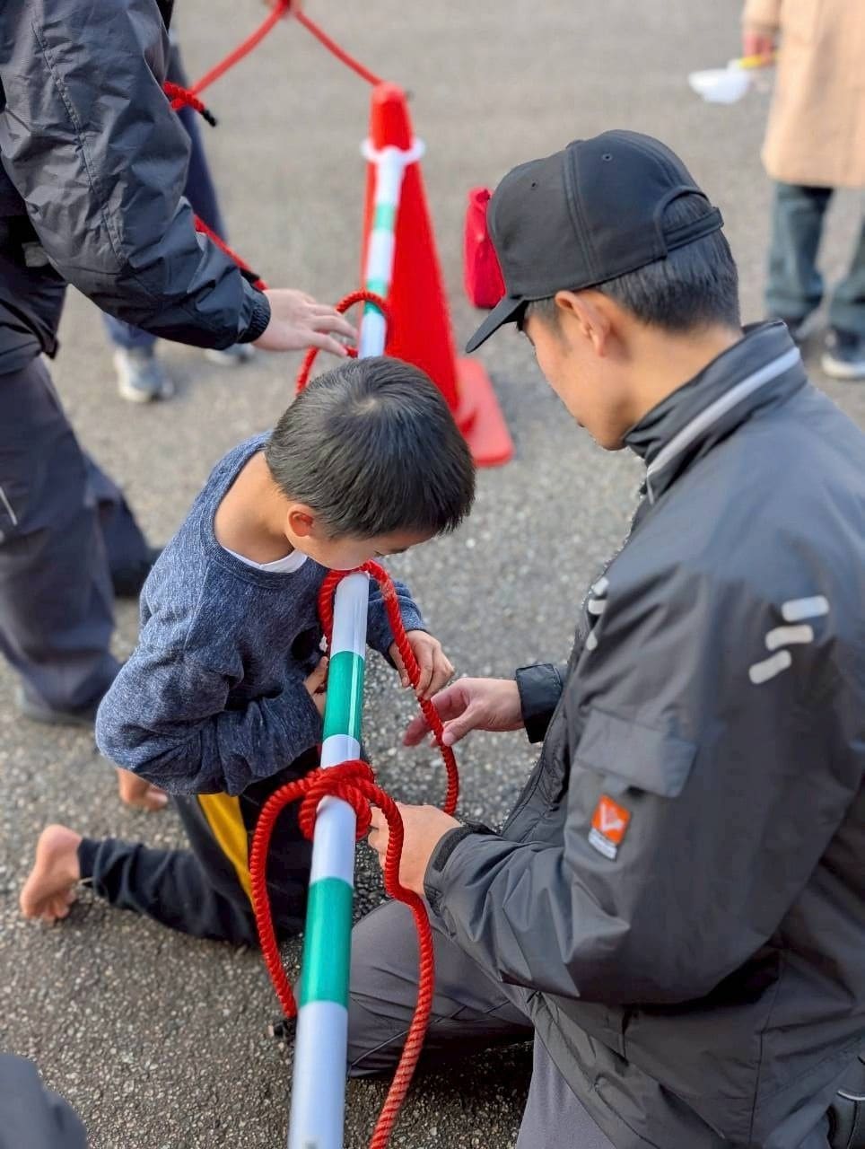 隊員からロープの結び方を教わる男の子